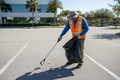 Worker picking up litter in a commercial parking lot